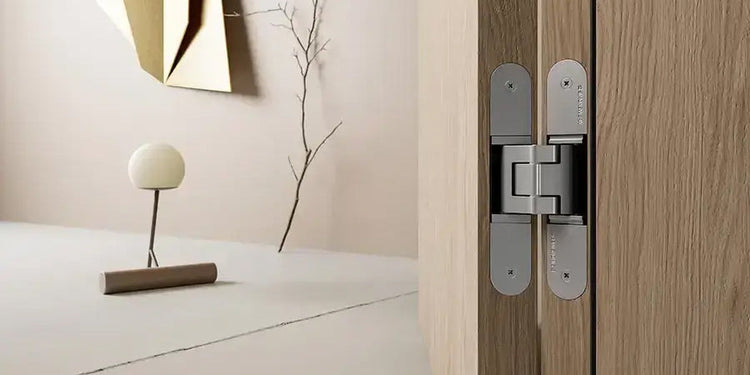 Simonswerk TECTUS concealed hinge in SSL F1 finish installed on a rebated oak wood veneer interior door, with a beige gasket (seal/weatherstrip). Showing 17 finishes of Tectus hinges from F1 to black to gold.