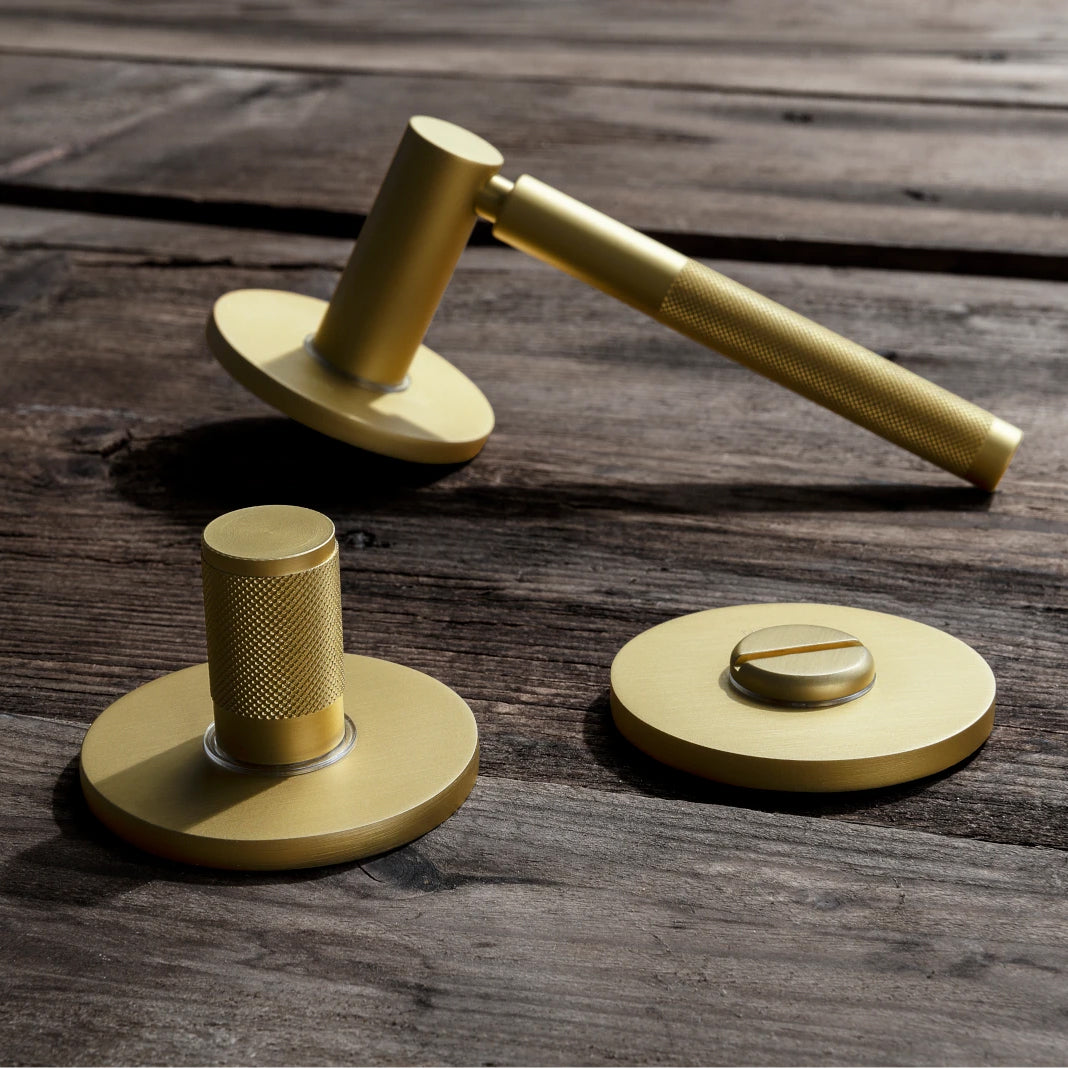 Gold colored knurled door handle by M&T with a privacy thumbturn,. Model M&T Touch in Titanium Brass Matte finish.